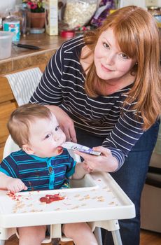 A woman feeds her baby juice in the kitchen