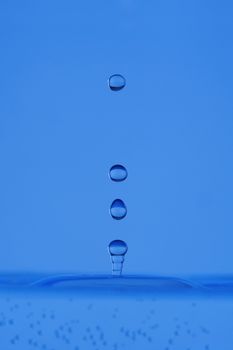 blue droplet hitting the water surface splashing it up