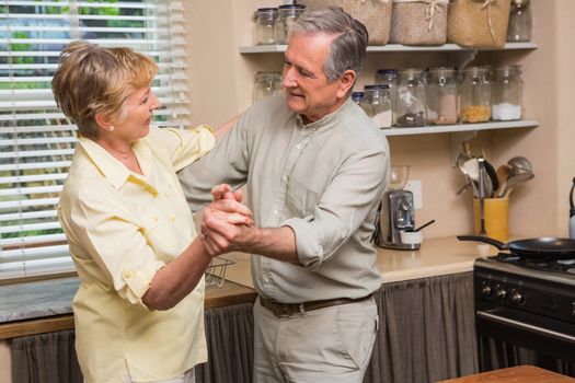 Romantic senior couple dancing together  at home in the kitchen