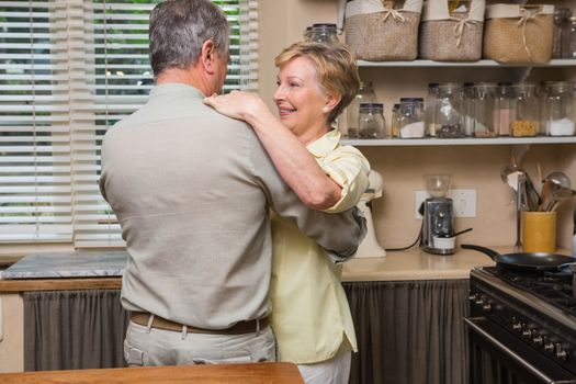 Romantic senior couple dancing together  at home in the kitchen