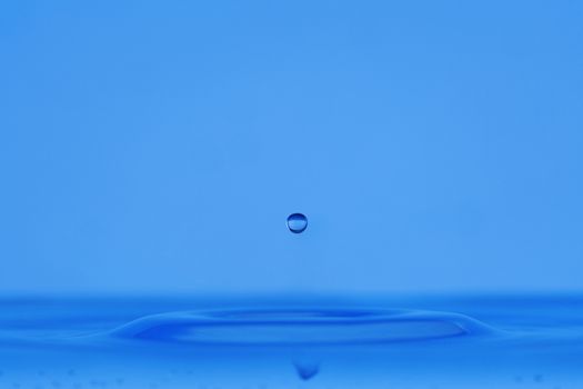 blue droplet hitting the water surface splashing it up