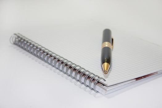 Black pen on the white paper notebook on the white background.