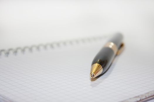 Black pen on the white paper notebook on the white background.