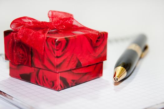 Ring gift box on the notebook with pen. Shallow depth of field.