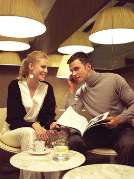 couple sitting in the cafe, both talking on their cell phones