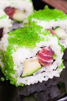 sushi roll set in green caviar on wooden background 