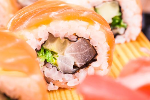 sushi roll set covered in salmon on wooden background 