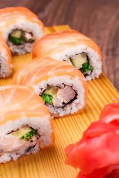 sushi roll set covered in salmon on wooden background 