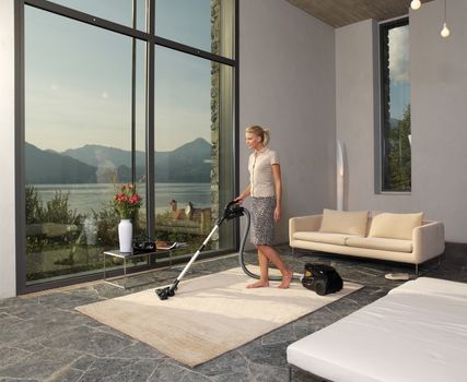 housewife with vacuum cleaner in a room