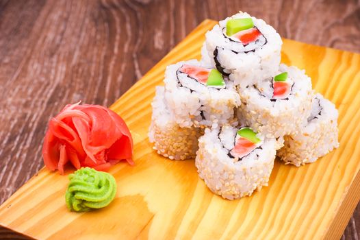 inside out sushi roll with salmon and avocado on wooden background 