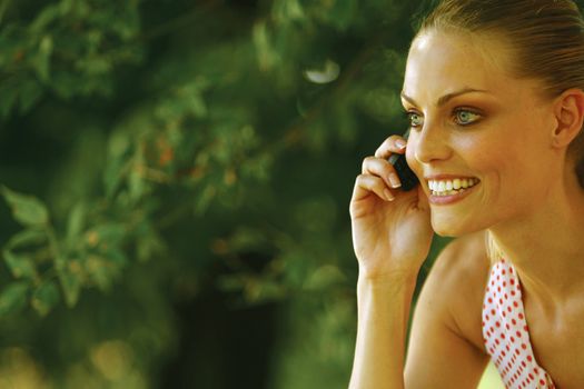 Young blond woman with mobile phone in the park 