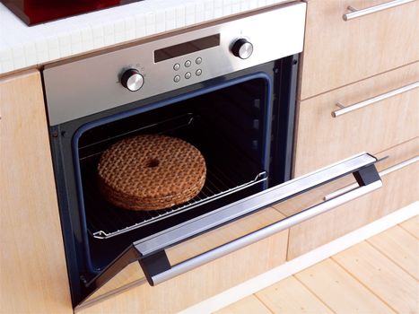 Open built-in electric oven with French fries and stainless steel cooking pots on stove