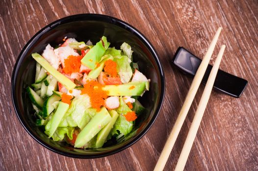 asian seafood and avocado salad on wooden background