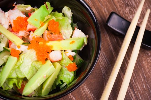 asian seafood and avocado salad on wooden background