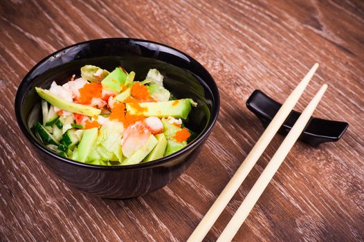 asian seafood and avocado salad on wooden background