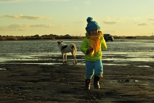 Running  little girl  on a sunset sandy autumn beach. Decline on the coast of the Ladoga Lake