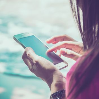 Woman using her Mobile Phone.on the beach Background.