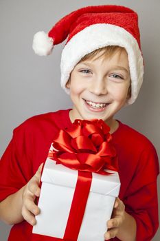 Smiling  funny child in Santa red hat holding Christmas gift in hand. Christmas concept.