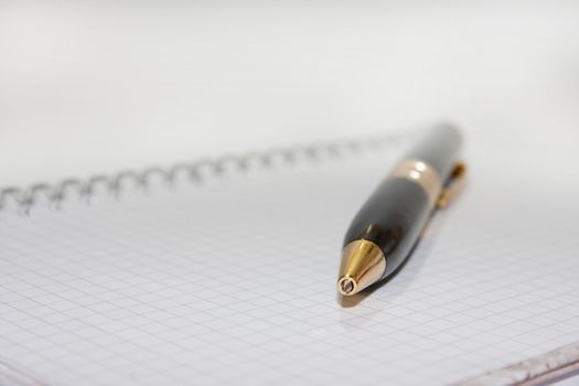 Black pen on the white paper notebook on the white background.