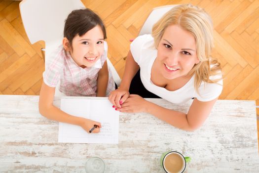 A mother helping her daughter with the homework seen from above.
