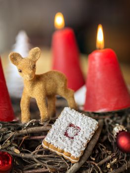 Detail shot of advent wreath burning red candle and deer kid.