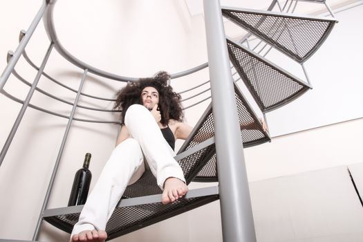 A young brazilian woman sitting on the stairs with a glass of red wine.