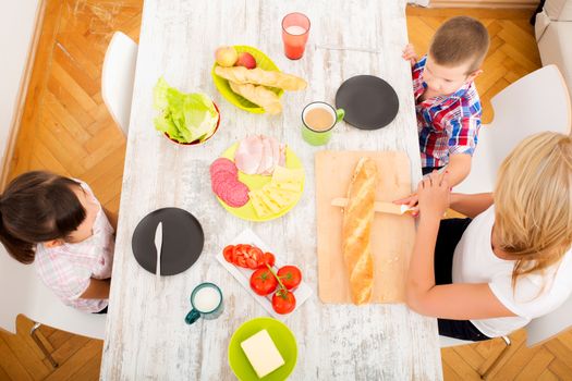 A mother and her children having breakfast at home.
