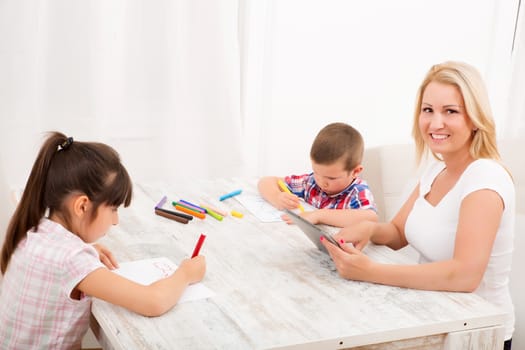 Mother and daughter and son at home at the table.
