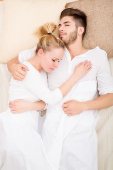 A happy young couple hugging in bed.
