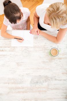 A mother helping her daughter with the homework seen from above.
