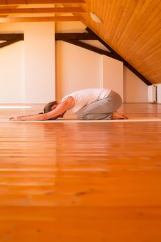 A young Woman practicing Yoga in a large attic Studio.