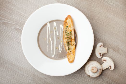 Vegetarian mushroom cream soup puree in white plate  with baked bread cheese slice