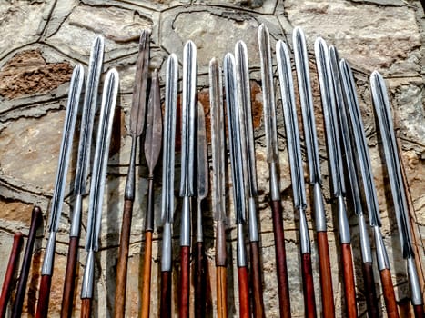 Masai spears resting against a stone wall, made the original way as they have alwasy been made.