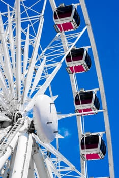 The pods of a white ferris wheel photographed against a very blue sky.