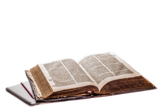 Old Dutch Bible on a white background with a modern notebook and pencil by the left of the bible.