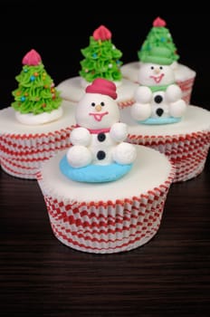Sugar Christmas snowmen figurines on glazed muffins
