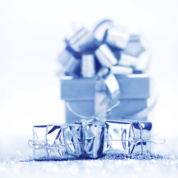 Silver holiday gifts on silver glitter background