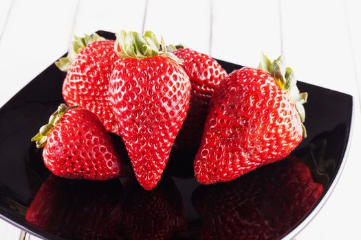 Red strawberries over black reflecting plate