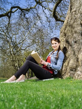 Photo of a young woman student studying outside under a tree.
