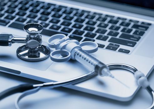 Stethoscope and syringe on laptop computer keyboard