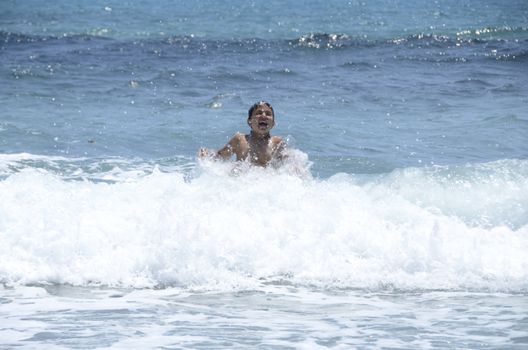 Happy summer for the child at the beach with the waves and splashing water.