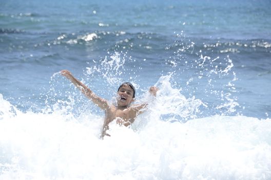 Happy summer for the child at the beach with the waves and splashing water.