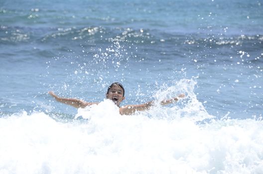 Happy summer for the child at the beach with the waves and splashing water.