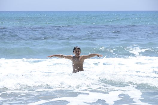 Happy summer for the child at the beach with the waves and splashing water.