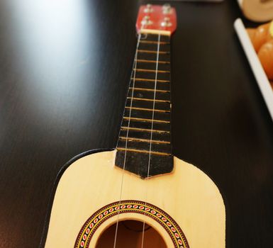 One guitar with light brown color placed on the shelves of home decor.                               