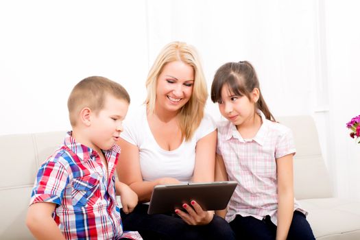 A mother using with her son and daughter a Tablet PC.
