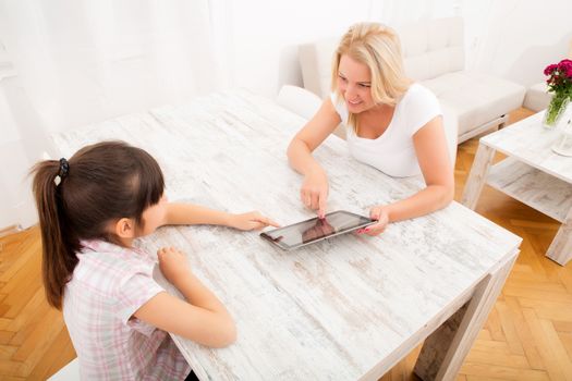 A mother with her daughter using a tablet PC at home.
