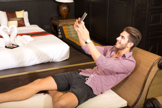 A handsome young man taking a selfie in a asian style hotel room.