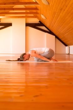 A young Woman practicing Yoga in a large attic Studio.