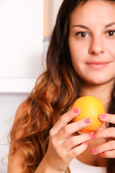 A young adult woman with fruits in the kitchen.